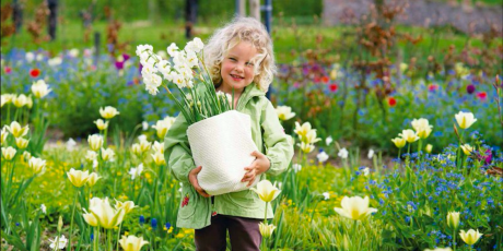 Das Mädchen mit den Blumen in der Hand im Garten
