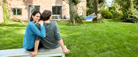 Ein junges Paar sitzt im Garten seines Hauses